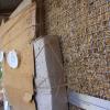 Cardboard and paper plates are affixed to a wall filled with hay.