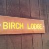 Brown sign that reads "Birch Lodge" in yellow.