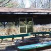 Screened-in Jack Pine Pavilion exterior, featuring a campfire area and wooden benches.