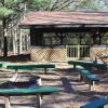 Screened-in Jack Pine Pavilion exterior, featuring a campfire area and wooden benches.