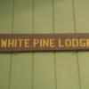 Brown sign with "White Pine Lodge" in yellow letters.