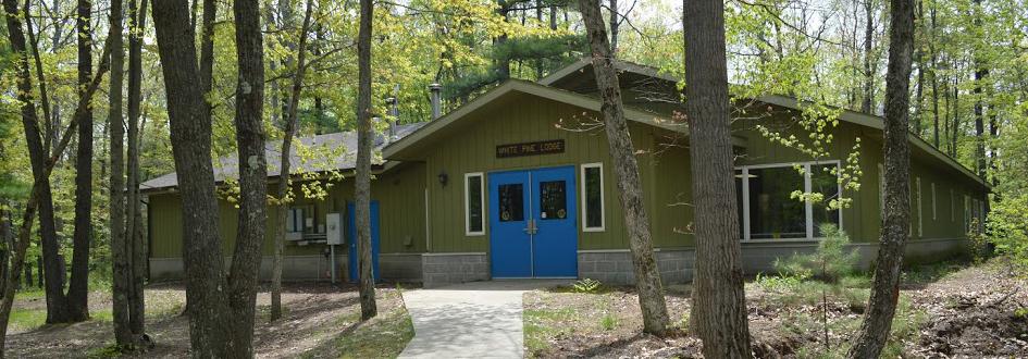 White Pine Lodge exterior in summer. The green building has bright blue doors.