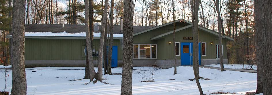 White Pine lodge exterior surrounded by snow. The green building has bright blue doors.